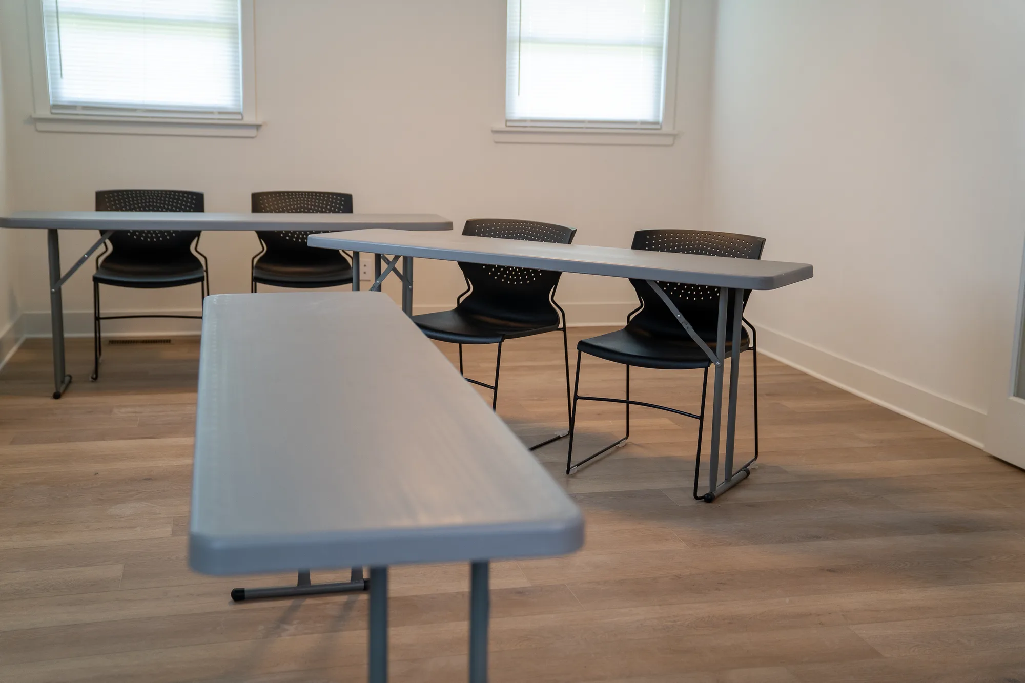 Tables and black chairs arranged for lessons in the academy classroom.