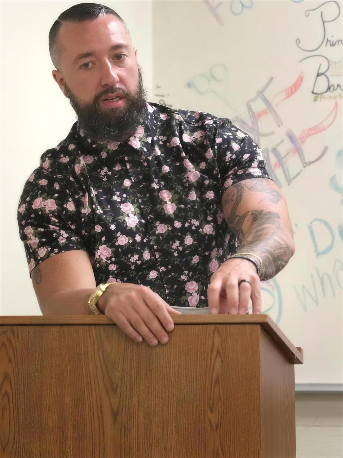 Justin Marlow speaking at a wooden podium in a classroom.